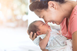 A woman smiles at a baby – attachment theory.